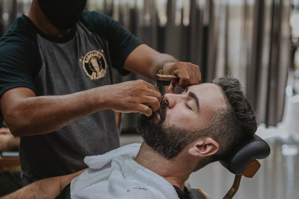 man in black crew neck t-shirt cutting hair of man